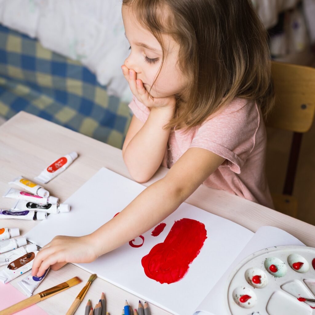 Cute little girl painting picture on home interior background